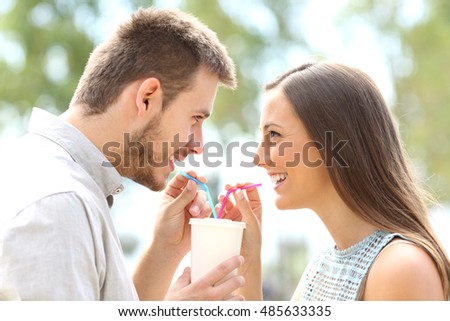 Side view of a happy couple falling in love and sharing a drink Royalty-Free Stock Photo #485633335