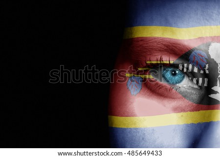 A young female with the flag of Swaziland painted on her face on her way to a sporting event to show her support.