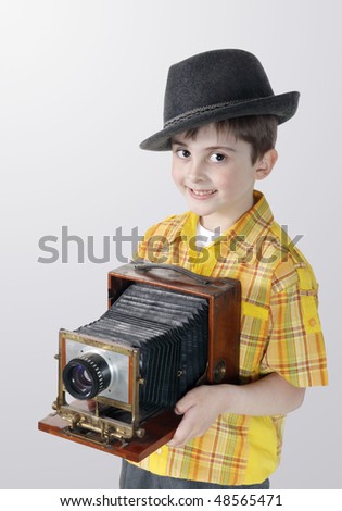 Little boy with an old camera on the grey background