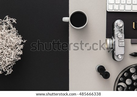 Photographer's desk with vintage camera, coffee and keyboard in black and grey. Flat lay with copy space. Modern and elegant.