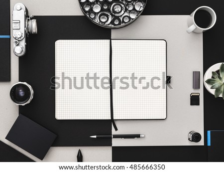Photographer's desk with scrapbook, vintage camera and coffee in black and grey. Flat lay. Modern and elegant.