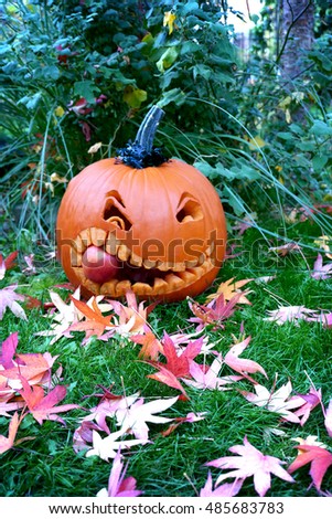 Halloween Pumpkin chewing on an apple, carved, autumn leaves and grass, portrait size