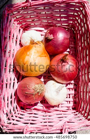 Cooking ingredients: onions and garlic in a pink basket