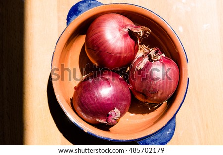 Three red onions on a cutting board