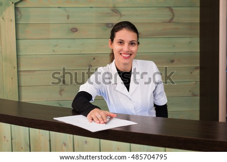 Woman on receptrion smiles and welcomes the virtual visitor at spa or modern clinic. Papers with agreement in your hand.