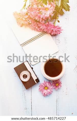 Cup of black coffee, Bouquet of flowers, Vintage camera  and Empty paper sheet on Rustic blue table from above, Beautiful retro card, Top view, copy space for text, flat lay concept