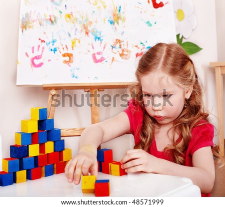  Child with wood block and construction set in play room. Preschool.