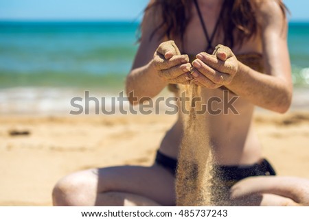 Sand as the time slips through your fingers. Girl holding a sand sea background