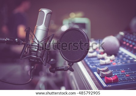 Professional condenser studio microphone over the musician blurred background and audio mixer, Musical instrument Concept Royalty-Free Stock Photo #485792905