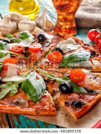 Close-up of Homemade delicious pizza with bacon, tomatoes, olives and basil top view over wooden background
