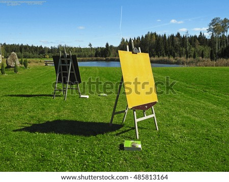 Wooden easel with blank canvas on summer green field
