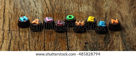 Halloween Day : colourful letter chocolate on wood background. Free space for text and selective focus.