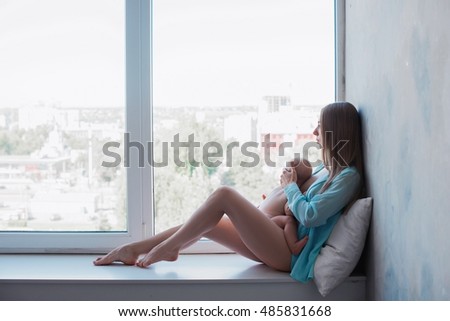 Baby in a tender embrace of yong mother at the windowstill,motherhood,family