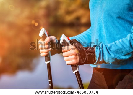 Nordic walking exercise adventure hiking concept - closeup of woman's hand holding nordic walking poles.  With lens flare and light leaks Royalty-Free Stock Photo #485850754