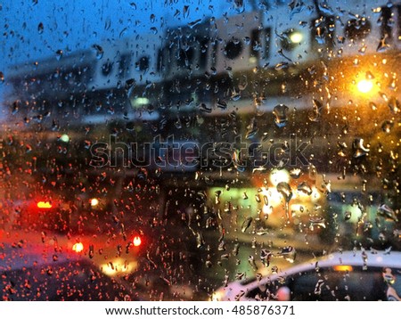 Water drops on a window glass after the rain with traffic background at evening. subject is blurred and low key
