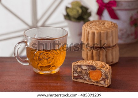 Chinese traditional moon cakes on wooden plate and table setting with teacup. Closeup, Select focus.