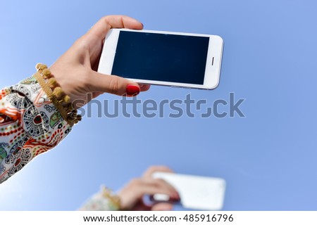 Hands of woman using cellphone with blank screen background