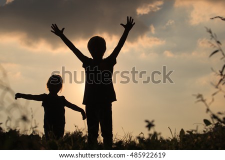 little boy and girl silhouettes play at sunset