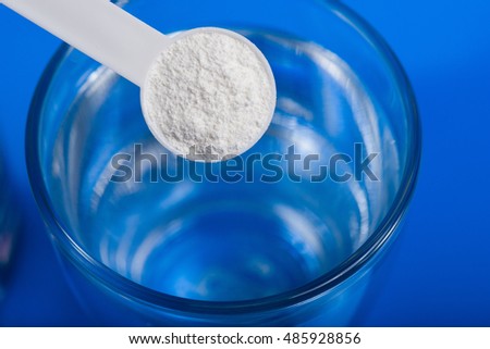 Sport supplement, creatine, hmb, bcaa, amino acid or vitamin - scoop with some powder over a glass of water. Sport nutrition or health concept.