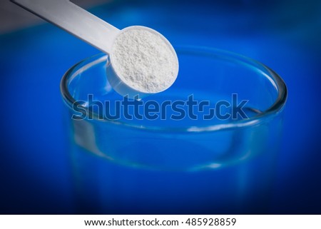Sport supplement, creatine, hmb, bcaa, amino acid or vitamin - scoop with some powder over a glass of water. Sport nutrition or health concept.