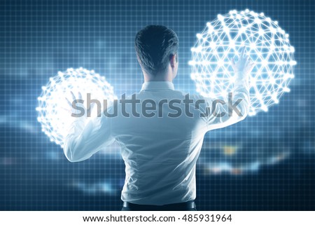 Back view of young business man controlling abstract digital models on city background