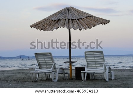 Empty deck chairs and bamboo umbrellas at the end of the day on the beach