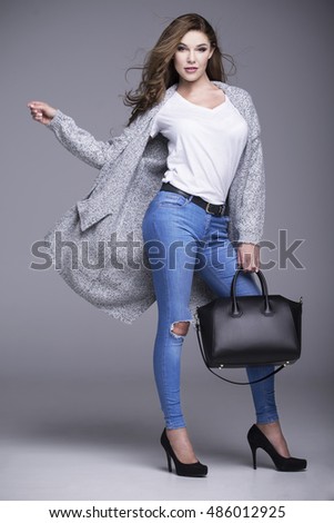 Beautiful young woman in a gray sweater and a black handbag