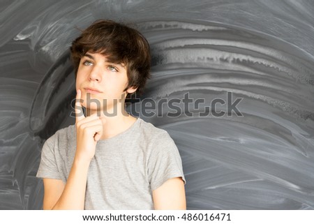 Tennage Boy thinking and getting an idea with empty blackboard in background
