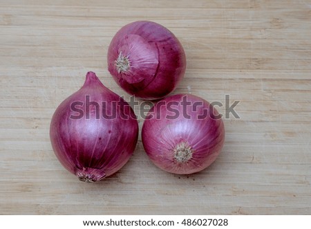 Three red onions on wooden background. Top View