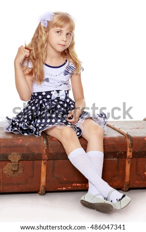 Distressed little girl with long blonde ponytails on her head, sitting on the old road suitcase-Isolated on white background