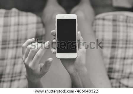 Black and white closeup picture on hand using mobile smart phone, background of copy space