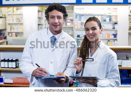 Portrait of smiling pharmacists with clipboard and digital tablet in pharmacy