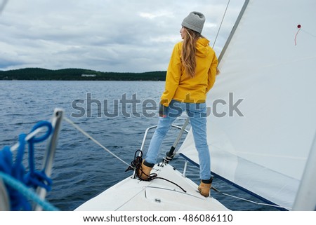 Young strong woman sailing the yacht on the bowsprit Royalty-Free Stock Photo #486086110