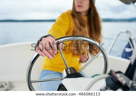 Young woman's hands on the steering wheel of the boat Royalty-Free Stock Photo #486086113
