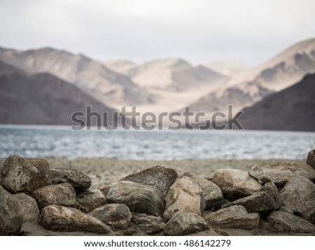 Close up of rock on the shore with blurred lake and mountain background