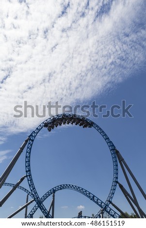 blue roller coaster loop with cart in front of blue sky