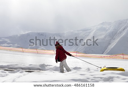 Girl with snow tube at sun day. Caucasus Mountains, Georgia, region Gudauri.
