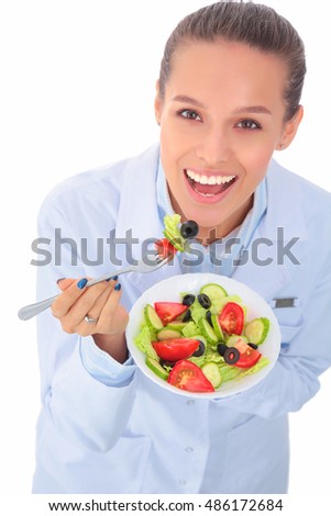 Portrait of a beautiful woman doctor holding a plate with fresh vegetables.