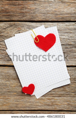 Red hearts and sheet of blank paper on a grey wooden table