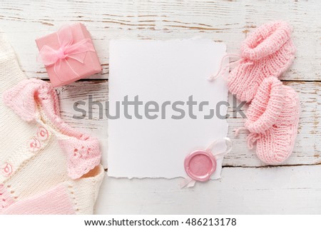 Baby girl clothes with blank card on wooden background. Flat lay. Owerhad view