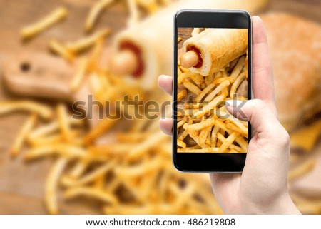 Woman taking a photo of Hamburger and fries with smartphone