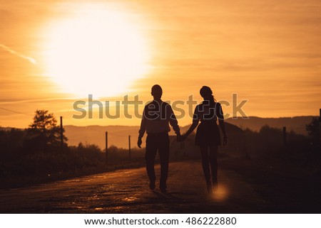 Warm picture of young couple holding each other hands during evening walk