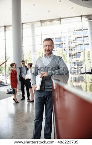 Businessman holding laptop leaning against reception desk