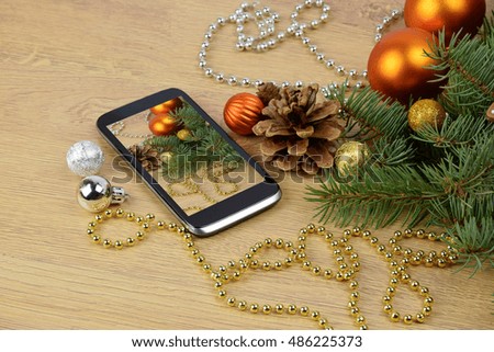 Festive greetings online. Xmas SMS. modern technologies.Modern Christmas present. Smartphone and branches of a Christmas tree on a wooden background.