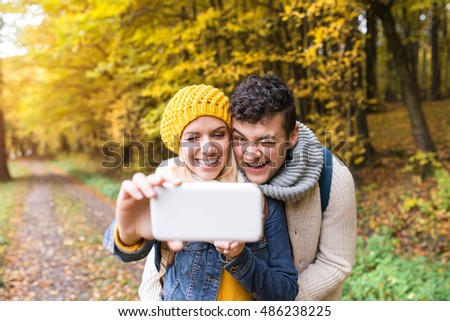 Beautiful young couple taking selfie in autumn forest