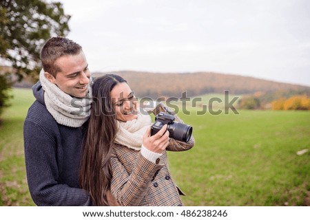 Beautiful young couple with camera taking pictures. Autumn natur