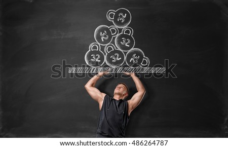 Muscled young man pushing off hand drawn surface with kettlebells. Weightlifting. Heavy weight. Picture on blackboard. Strength and beauty.