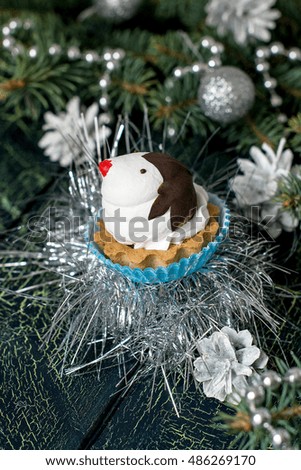 Christmas cupcakes in the shape of funny penguins of meringue with chocolate on background decorated Christmas tree on a blue-green cracked background. Selective focus