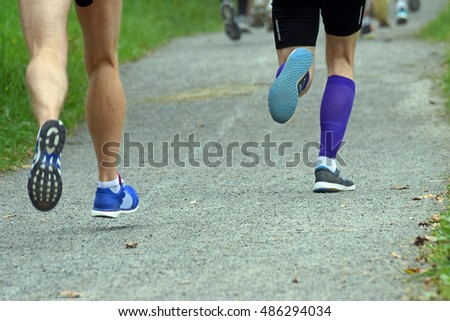Rear view of runners legs. Close up of two men jogging on walkway.  Horizontal low angle view with copy space. Royalty-Free Stock Photo #486294034