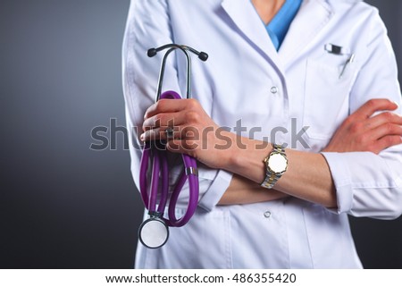 Portrait of young female doctor holding a stethoscope, isolated on black background